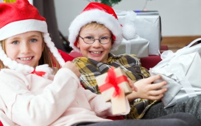 Portrait of happy kids opening their presents on Christmas day.